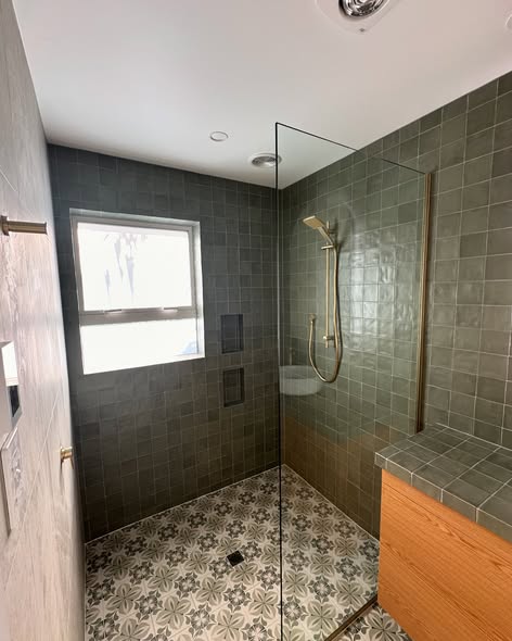 Green tiled walk-in shower with glass panel