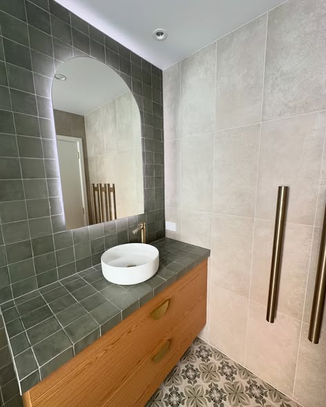 Powder room with green tiled wall and patterned floor